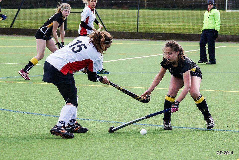 A girl with the number 15 on her shirt is playing field hockey