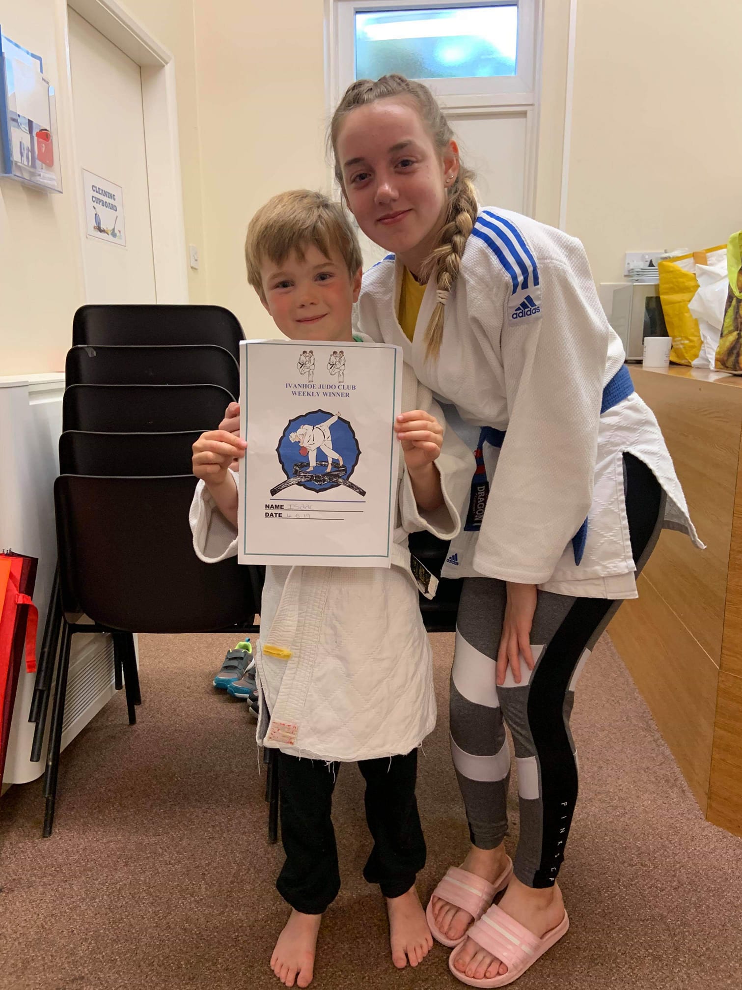 A girl and a boy are standing next to each other holding a picture.