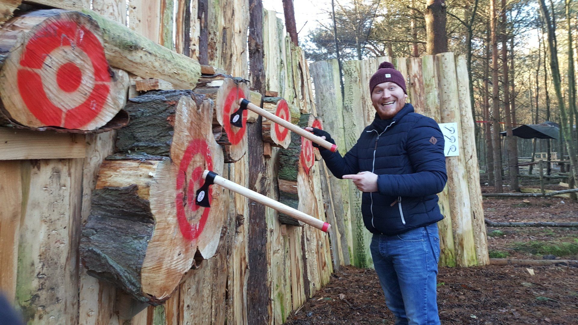A man is throwing axes at a wooden wall.