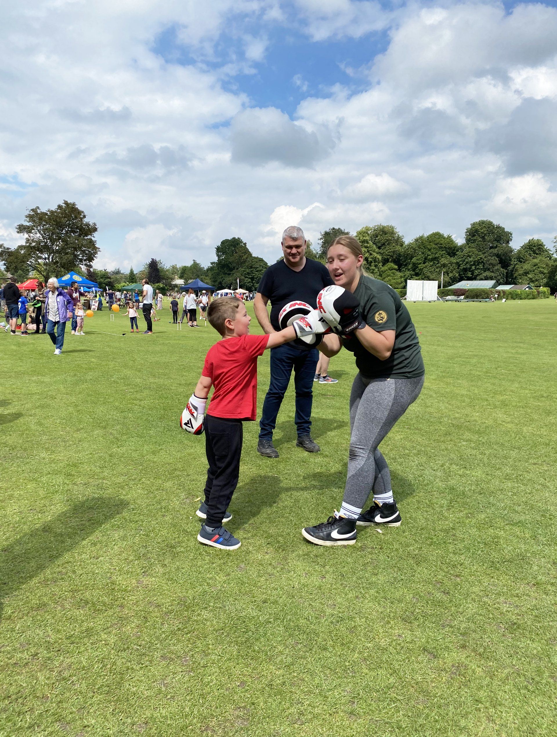 A woman and a boy are boxing in a field.