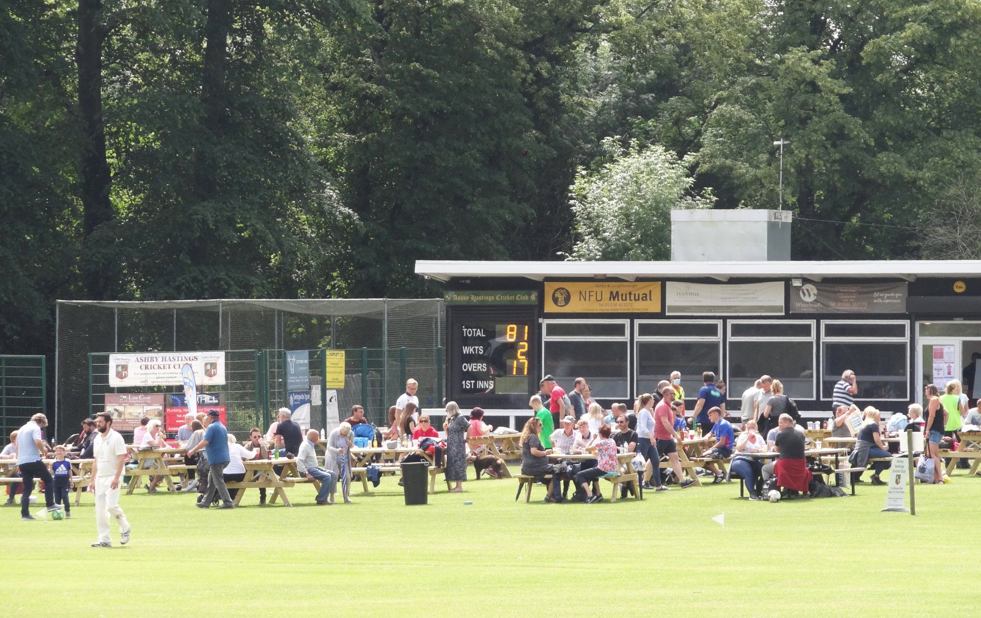 A group of people sitting at picnic tables in a field