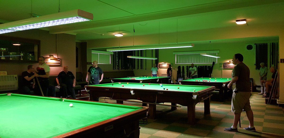 A man is standing in front of a pool table in a pool hall.