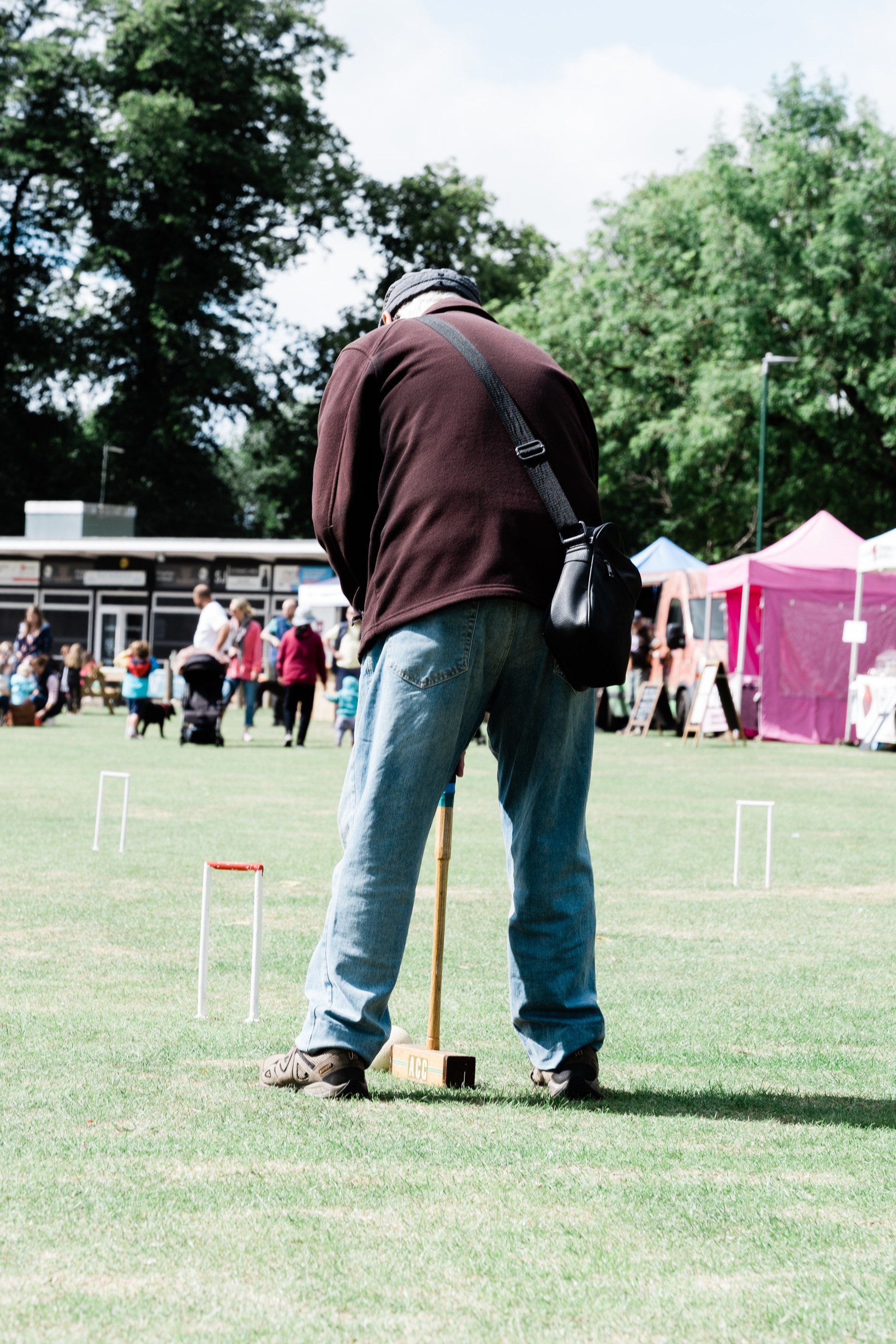 A man is playing a game of croquet in a field.