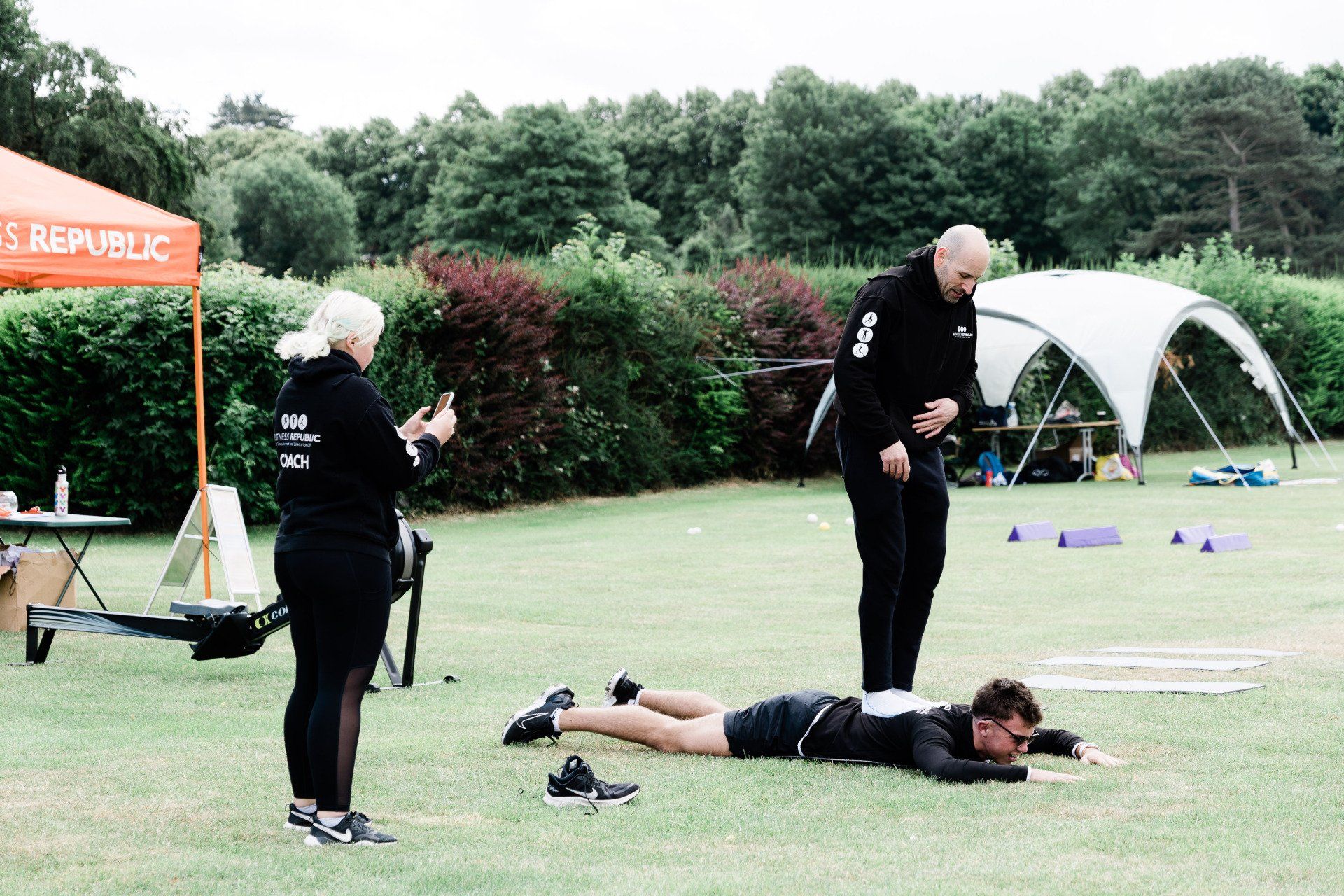 A group of people are standing around a man laying on the grass.