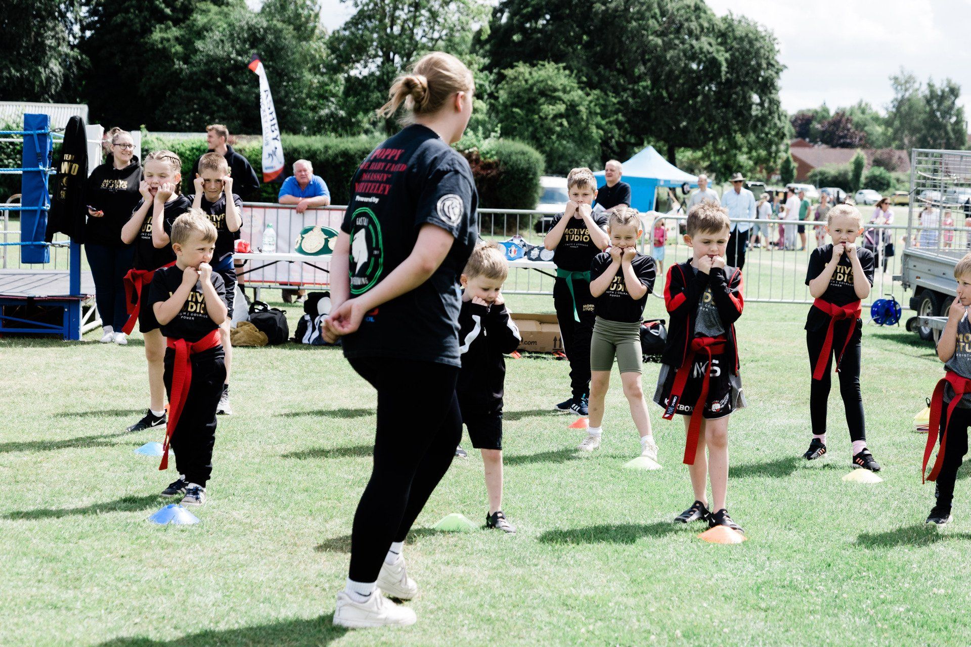 A woman is teaching a group of children martial arts in a park.