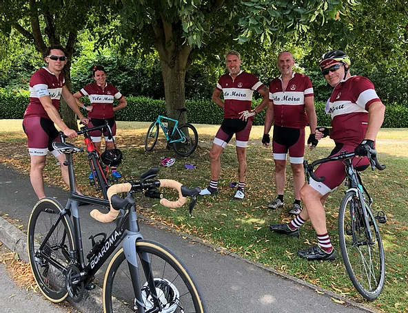 A group of people are standing next to bicycles in a park.
