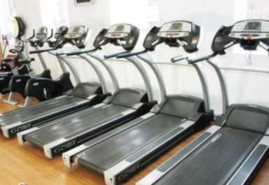 A row of treadmills are lined up in a gym.