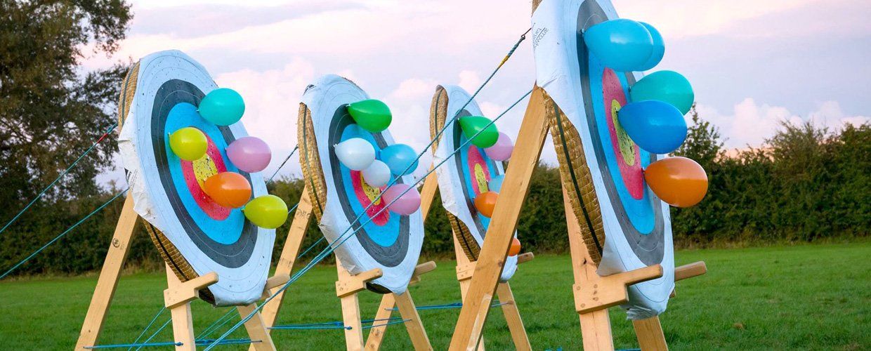 A group of archery targets with balloons on them in a field.