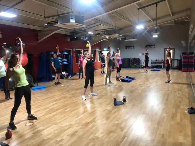 A group of people are doing exercises in a gym.