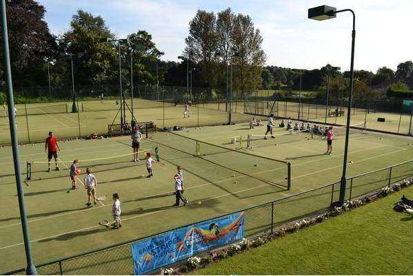 A group of people are playing tennis on a tennis court