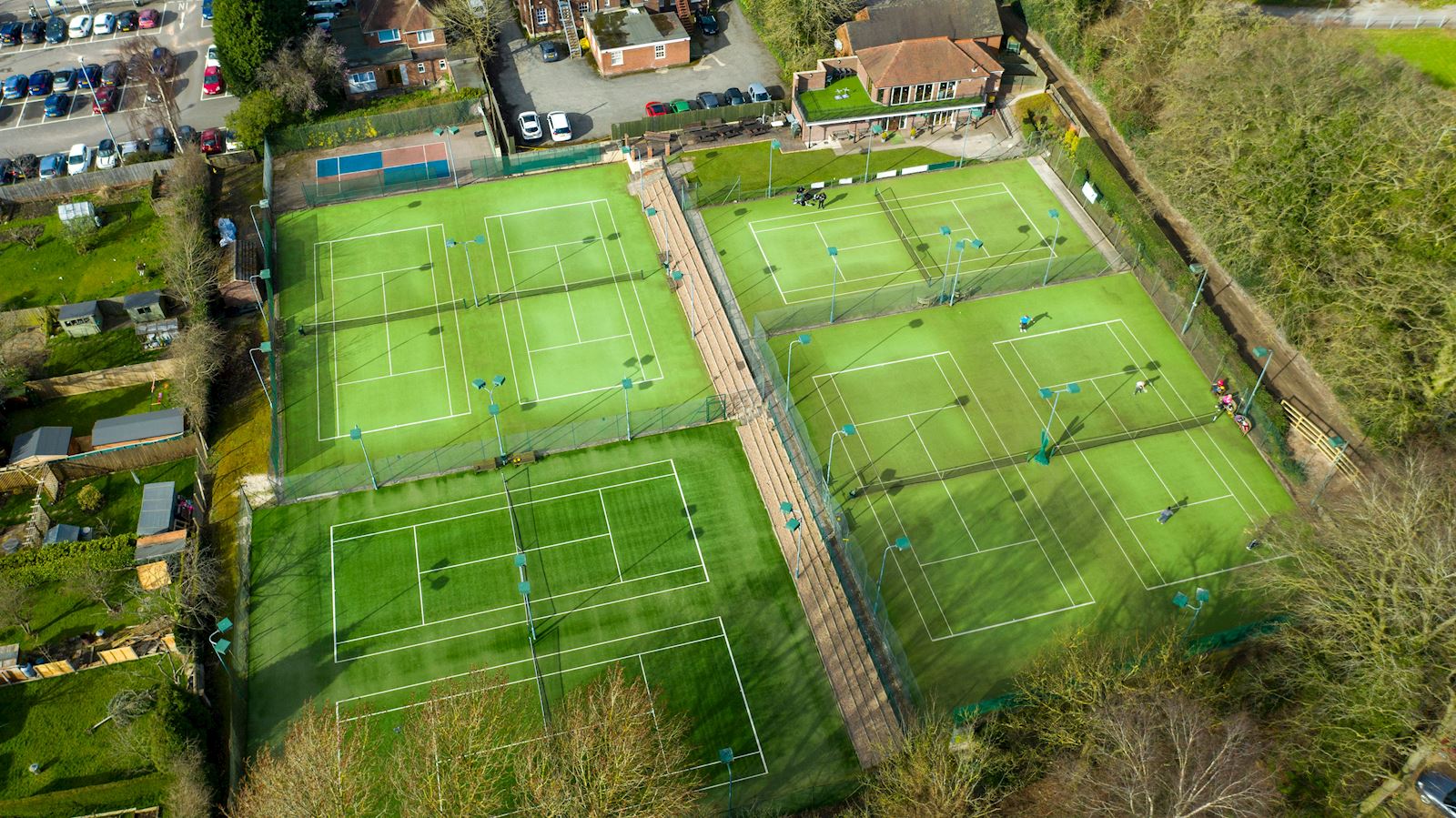 An aerial view of a tennis court in a residential area.