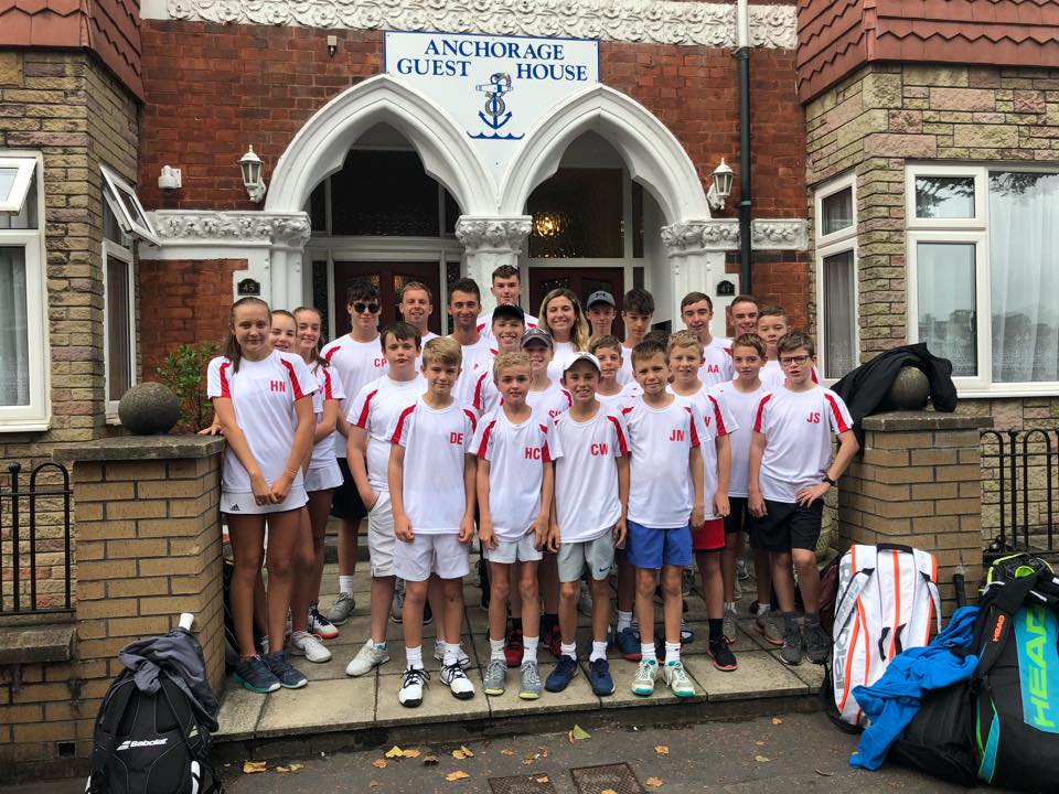 A group of young people are posing for a picture in front of the anchorage guest house.