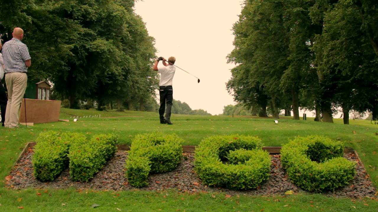A man is swinging a golf club on a golf course.