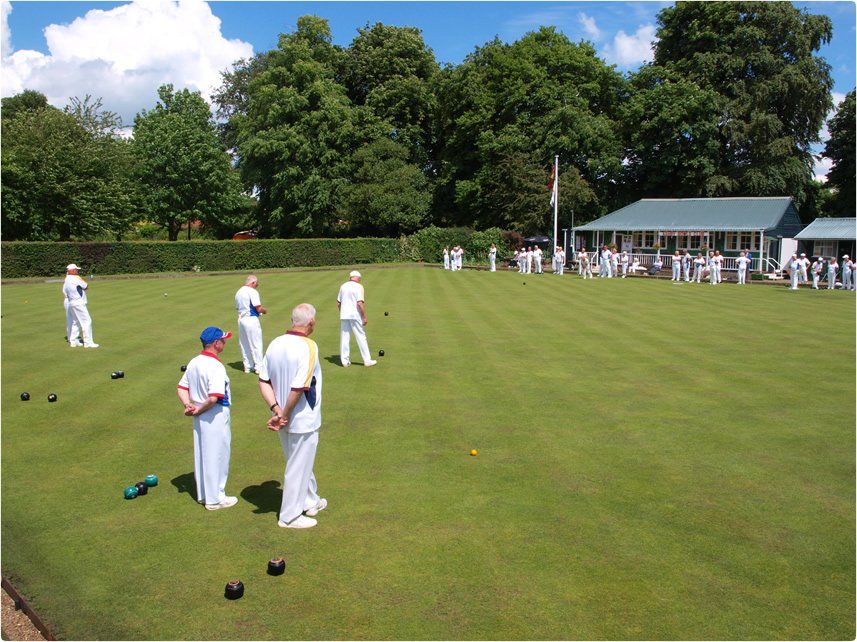A group of people are playing lawn bowling on a lush green field
