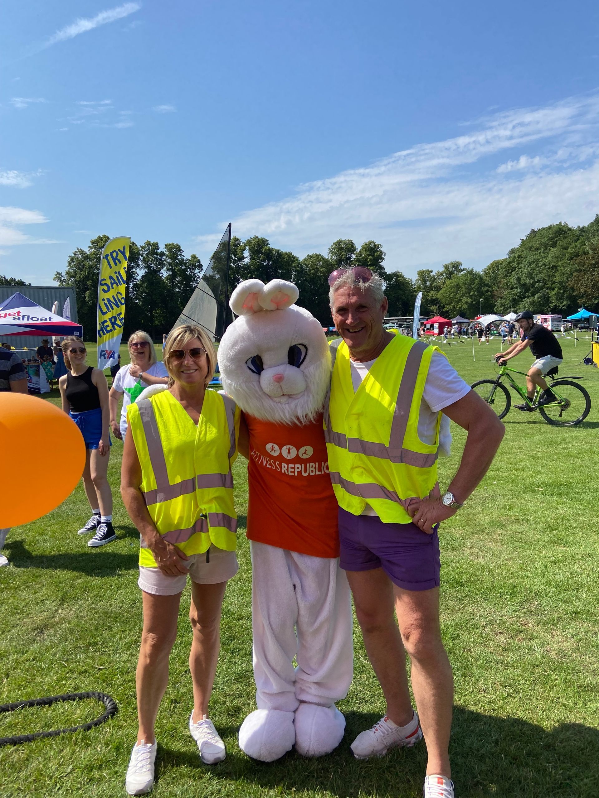 A man and a woman are standing next to a mascot in a field.