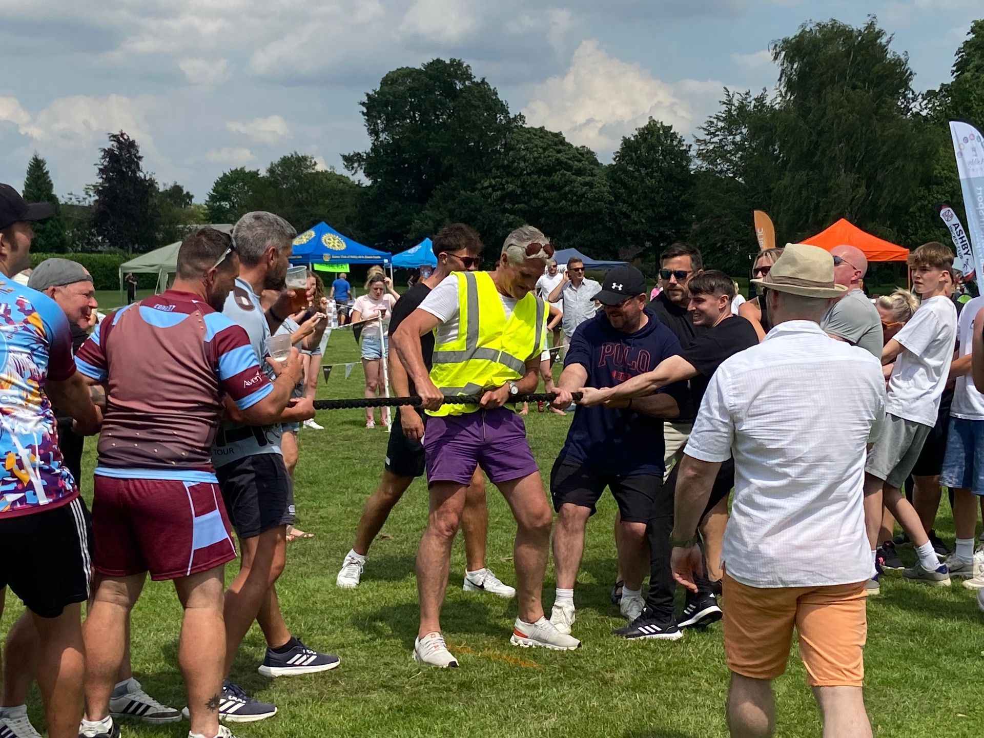 A group of men are pulling a rope in a field.