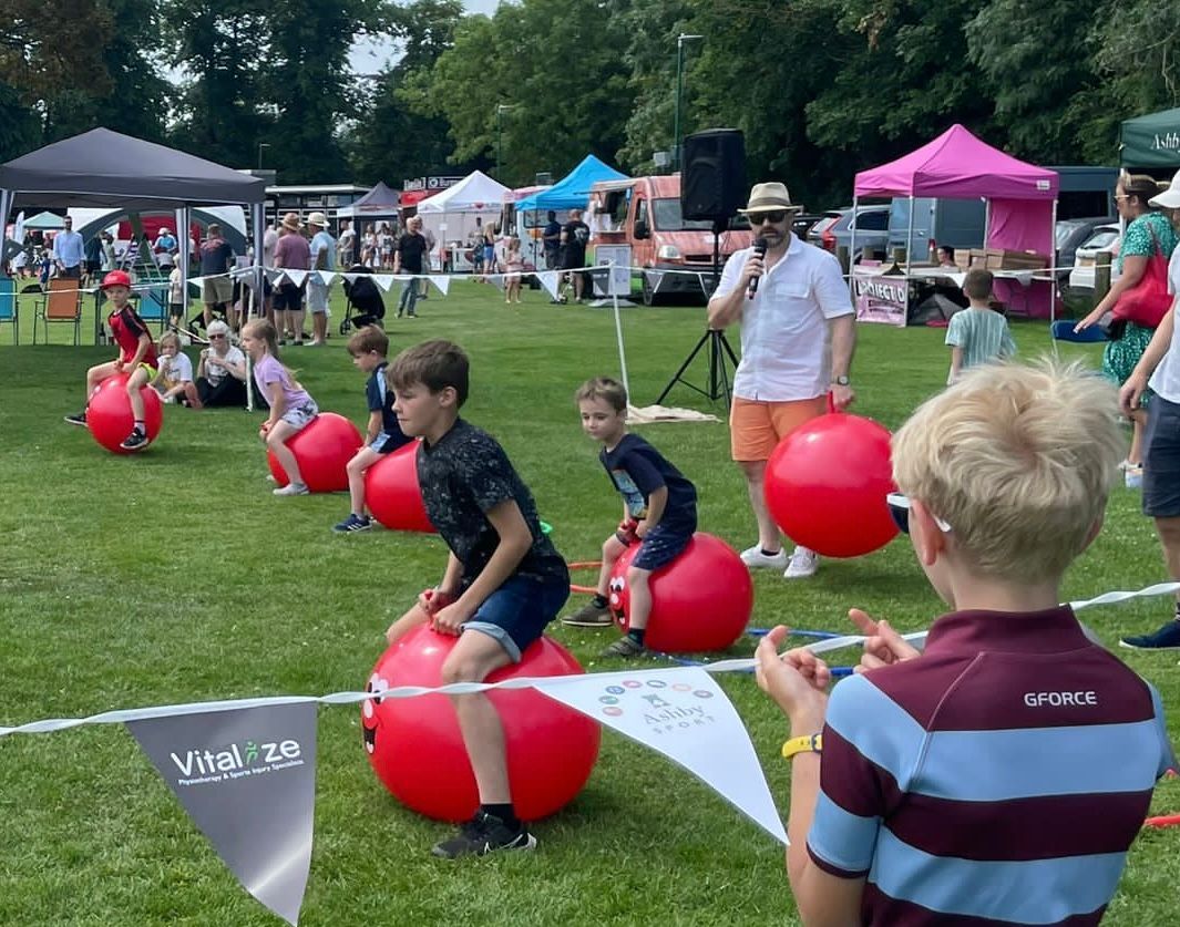 A group of children are sitting on red balls in a field.
