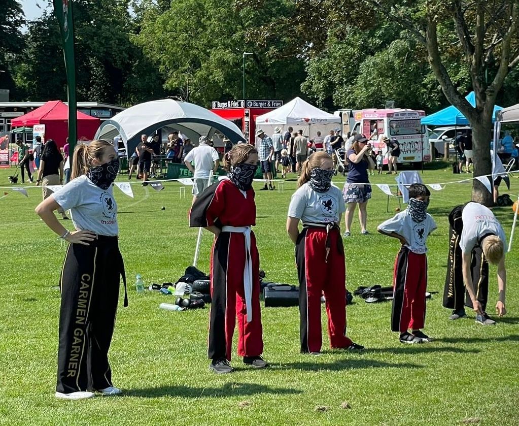 A group of people wearing masks are standing in a grassy field.
