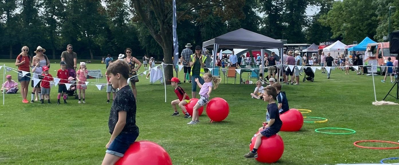 A group of children are playing with red balls in a park.