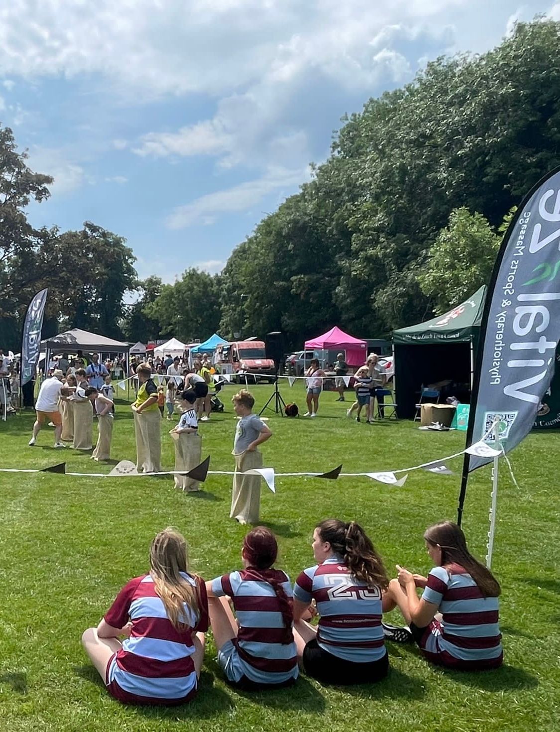 A group of people are sitting on the grass watching a race.