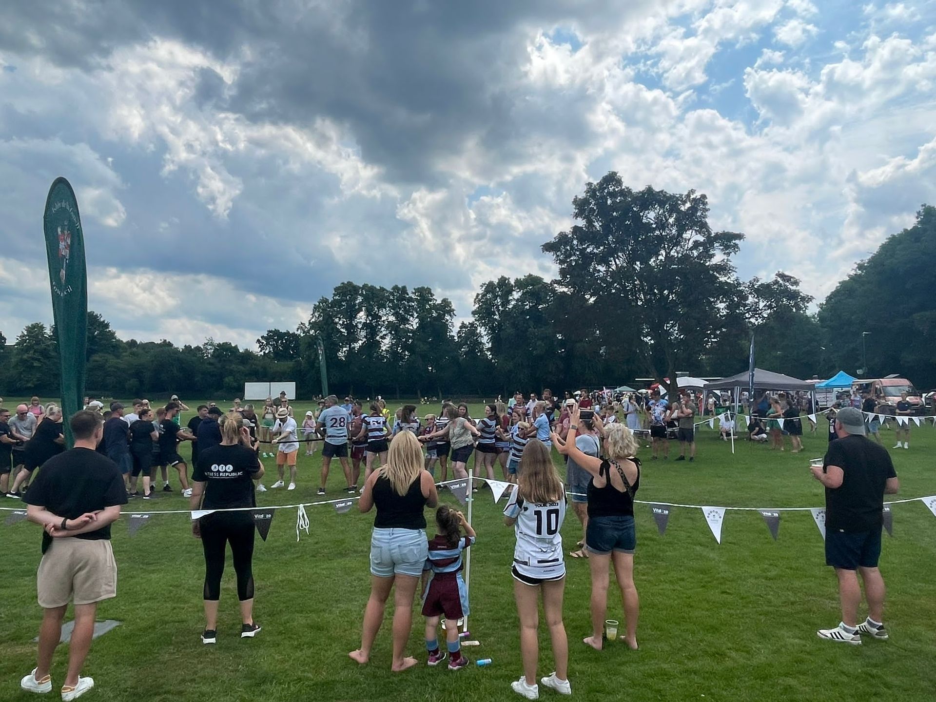 A group of people are standing in a field watching a game.