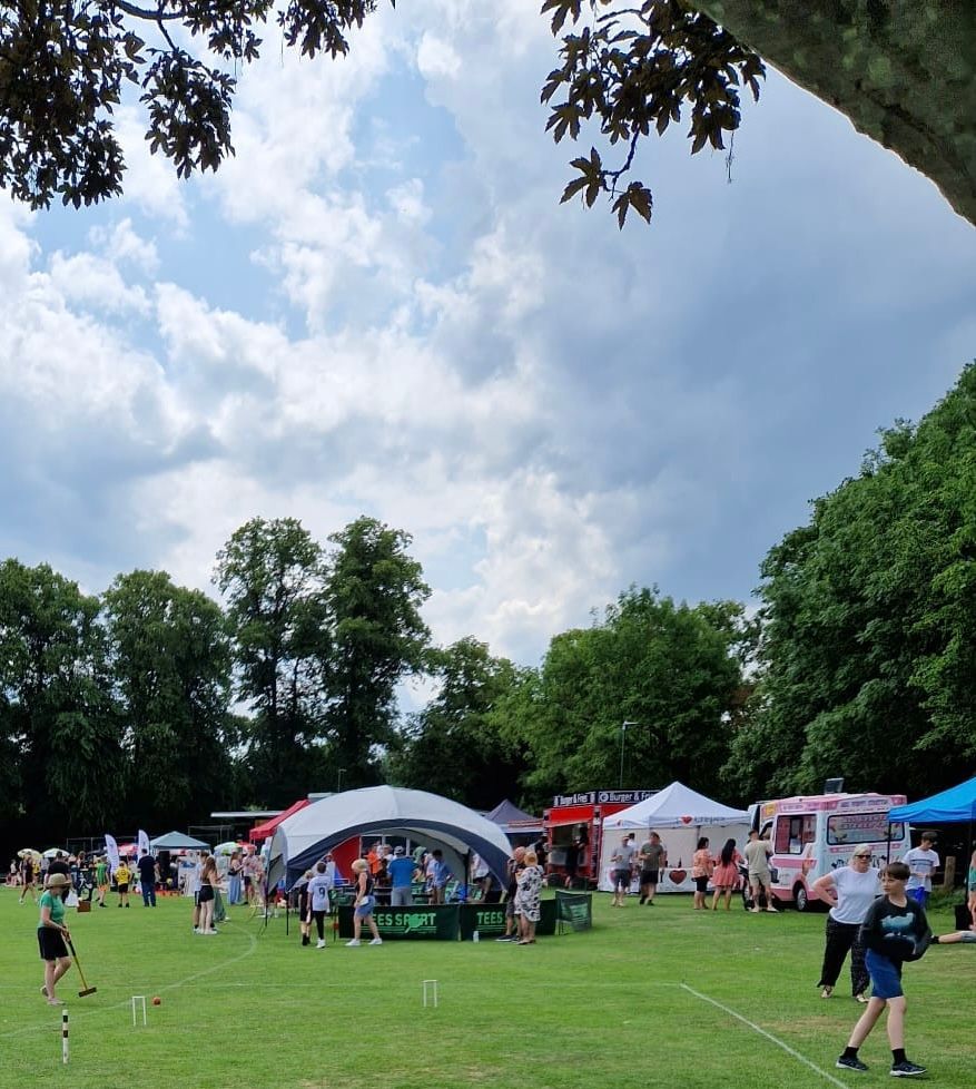A group of people are gathered in a grassy field with a tent that says ' ice cream ' on it