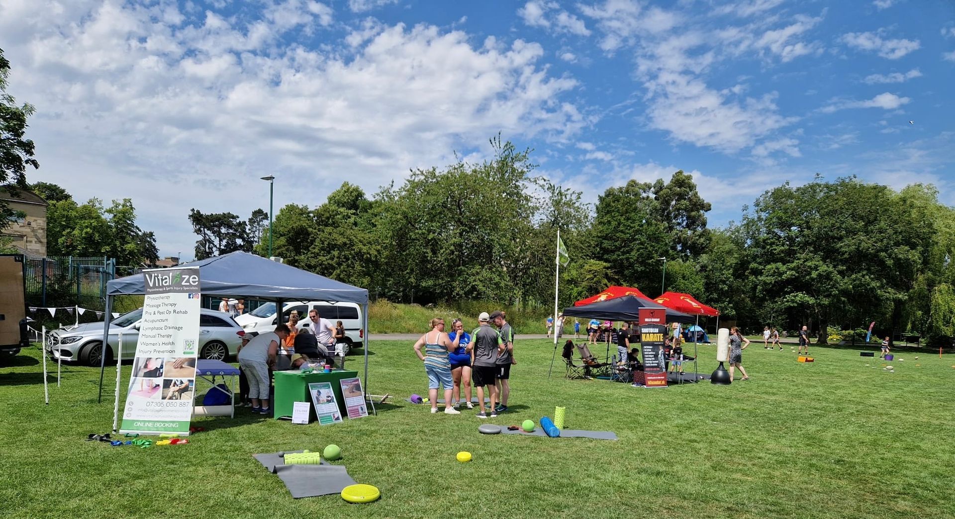 A group of people are standing around a tent in a park.