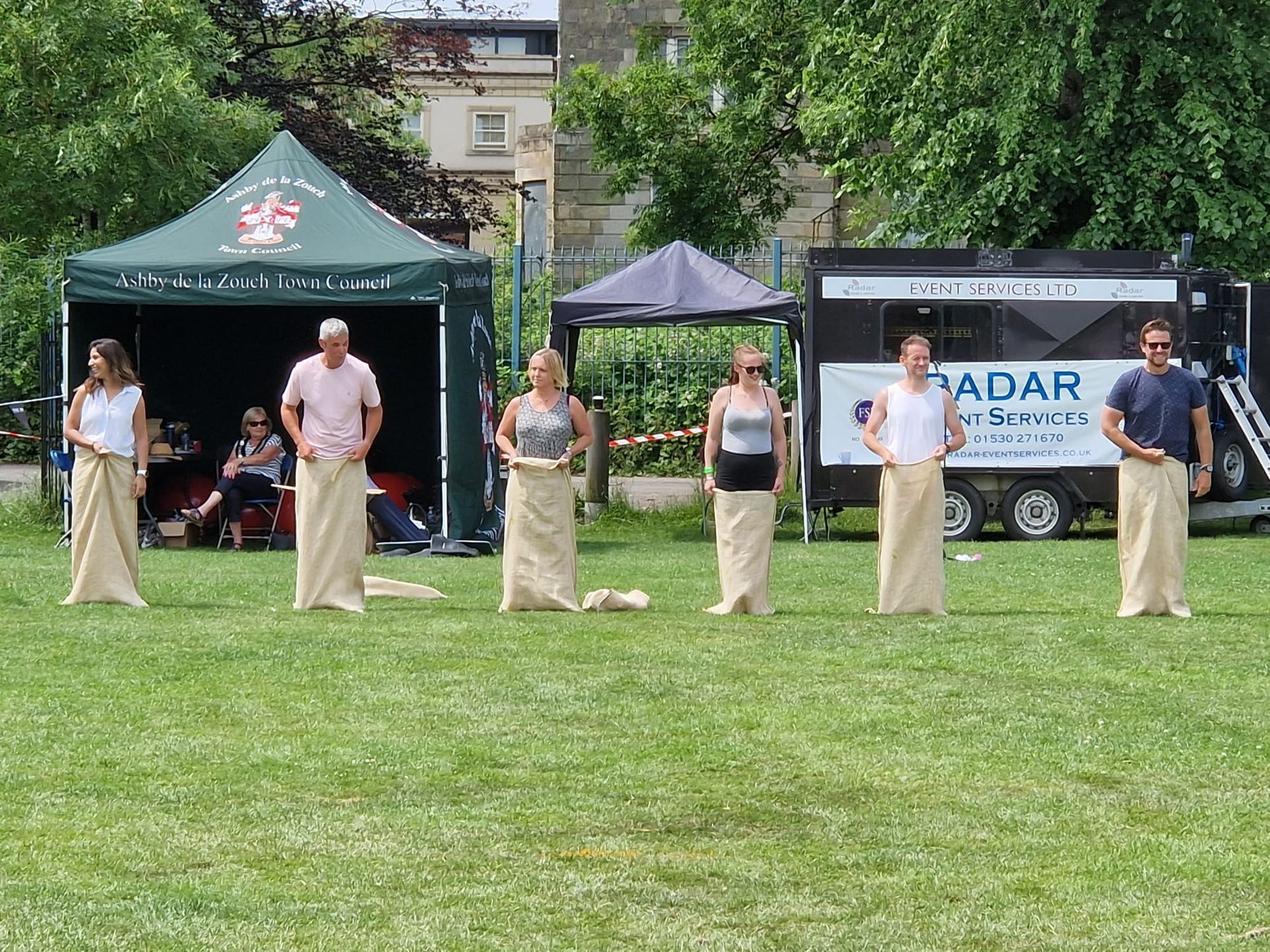 A group of people are standing in a field wearing sacks.