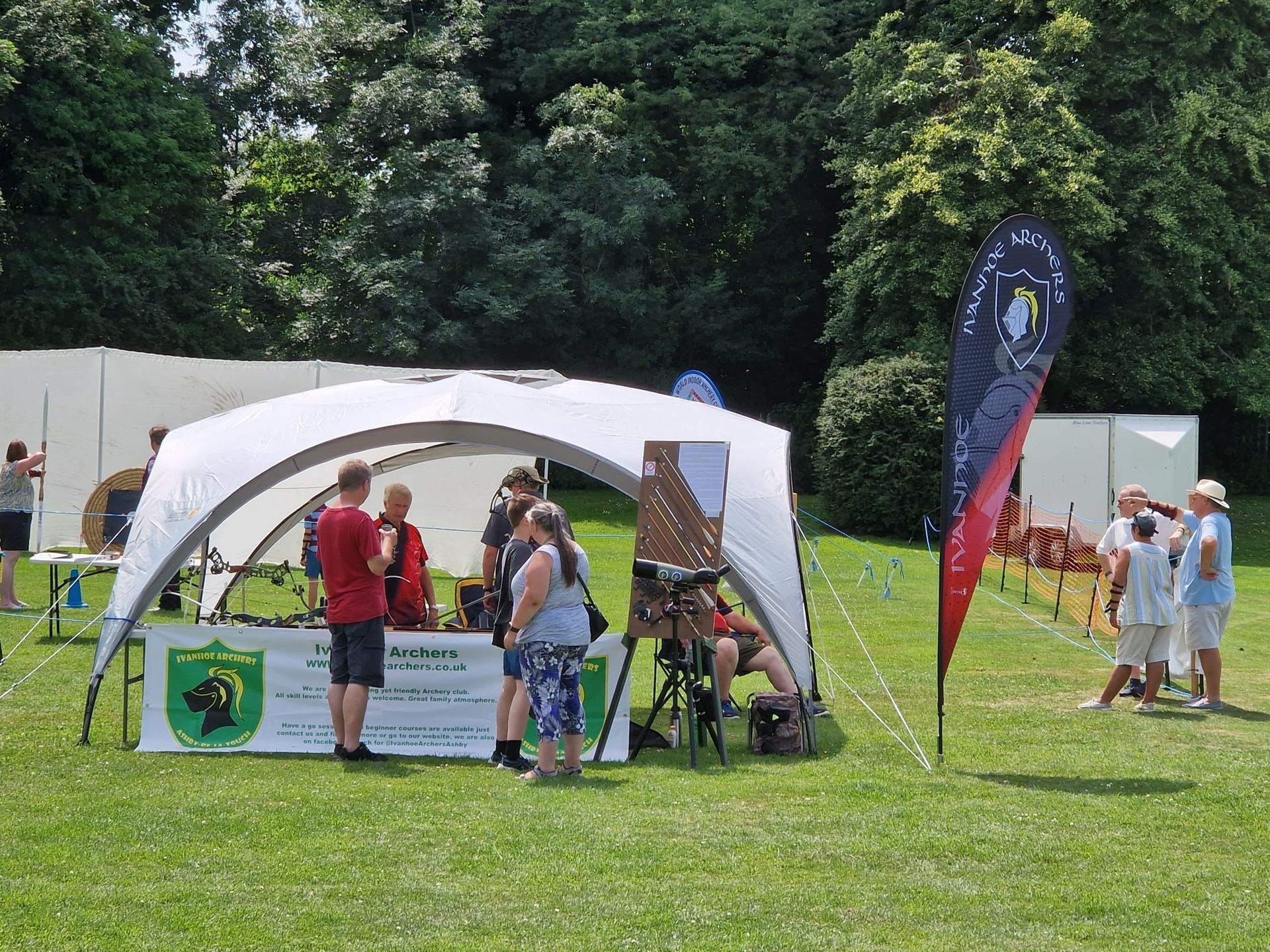 A group of people are standing around a tent in a field.