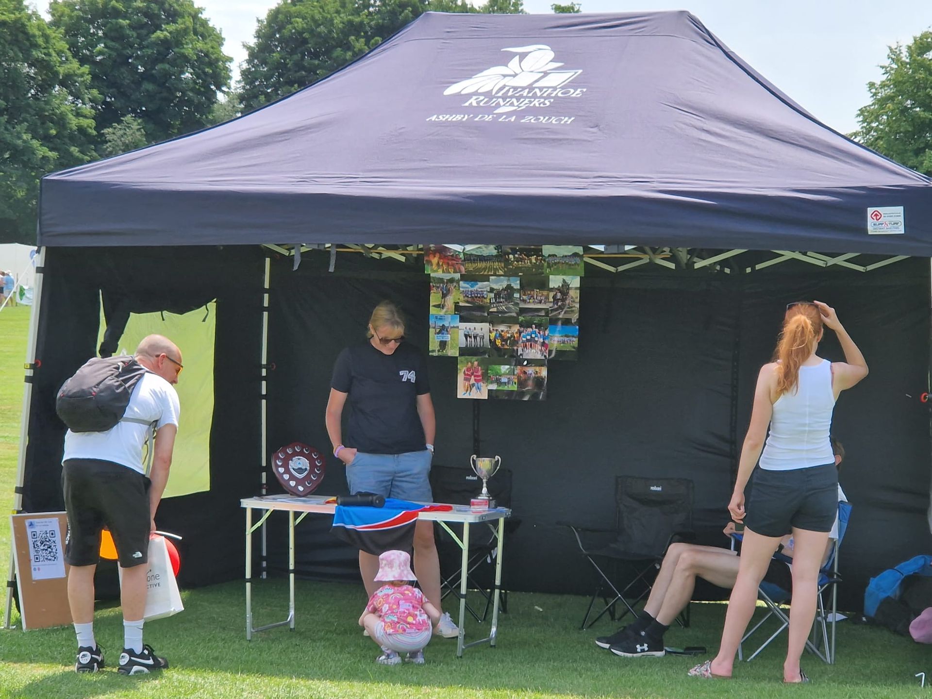 A group of people standing under a tent that says ' rugby ' on it