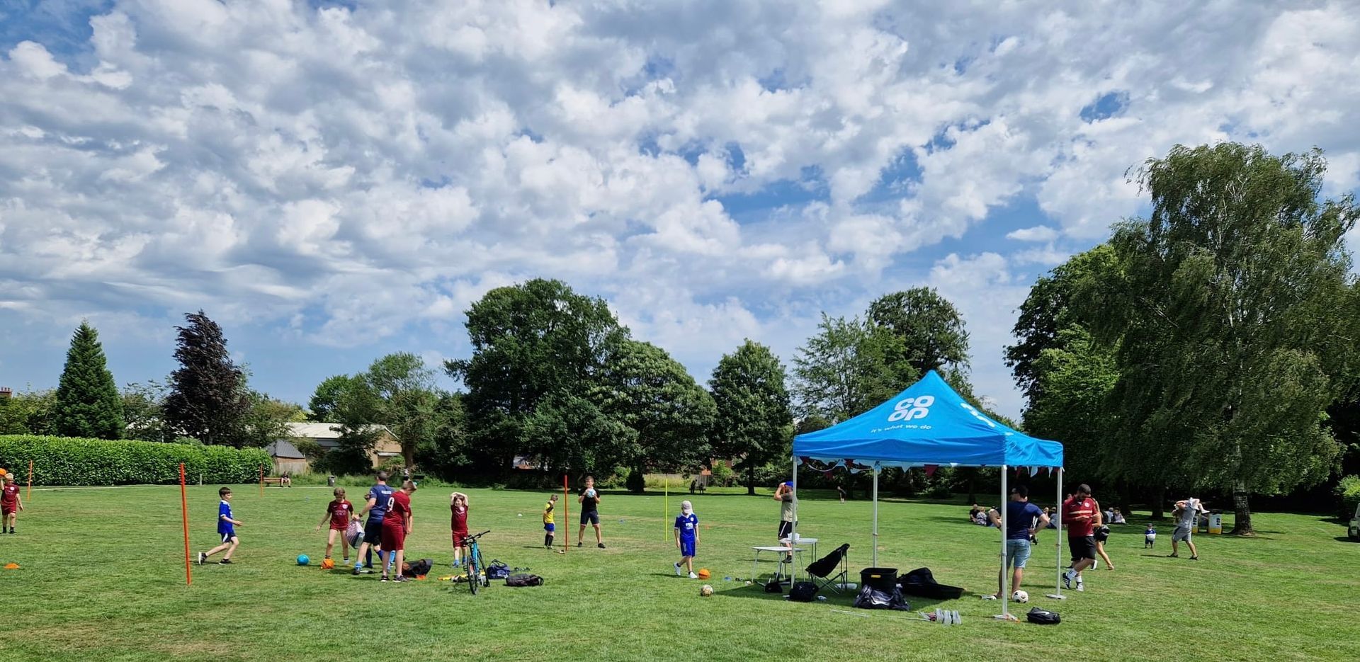 A group of people are standing in a field with a blue tent.