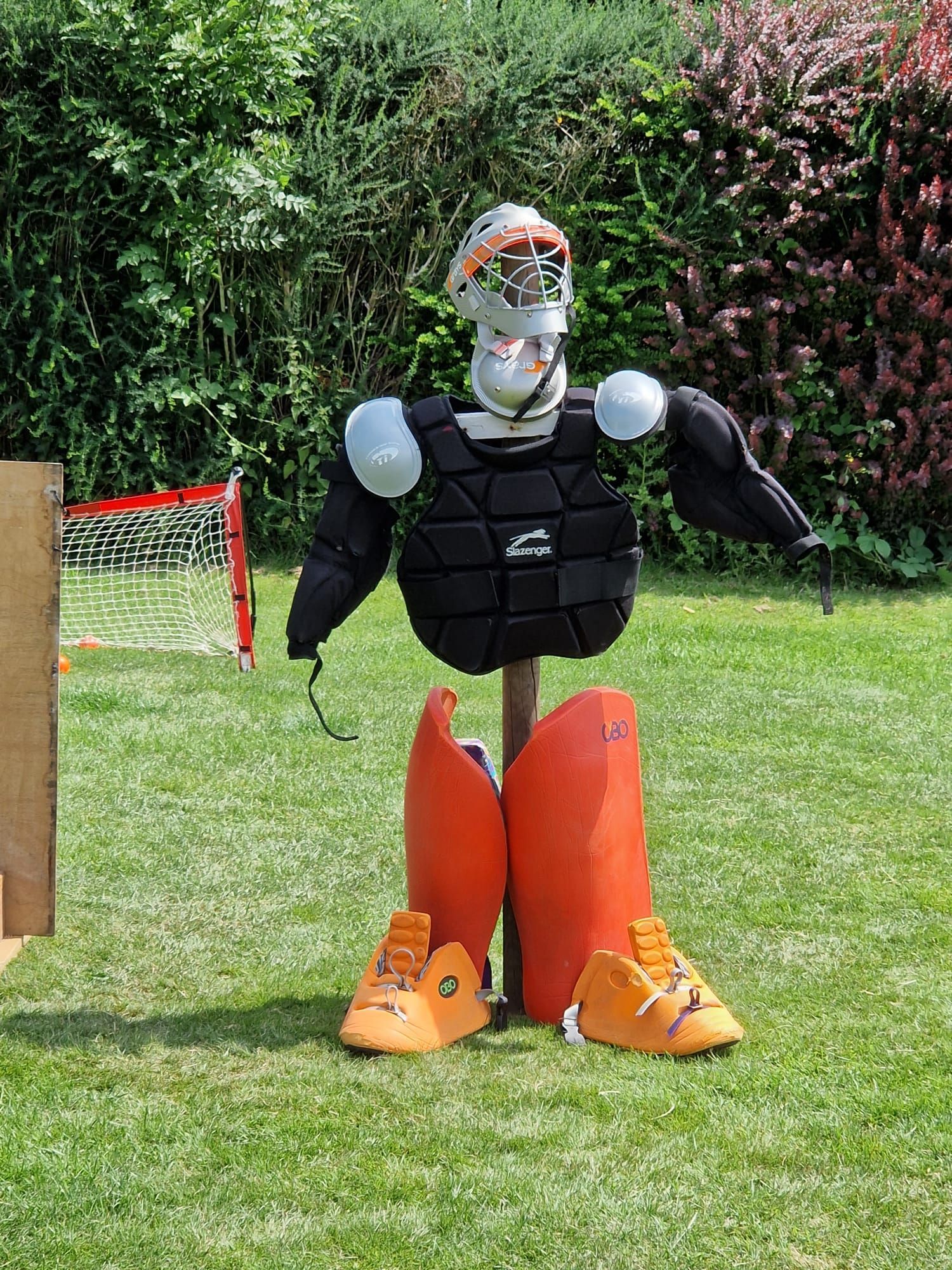 A scarecrow dressed as a hockey player is standing in the grass.