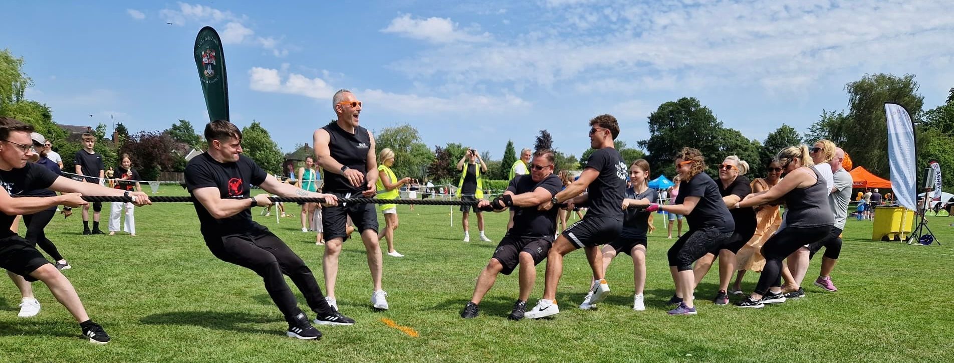 A group of people are pulling a rope in a field.
