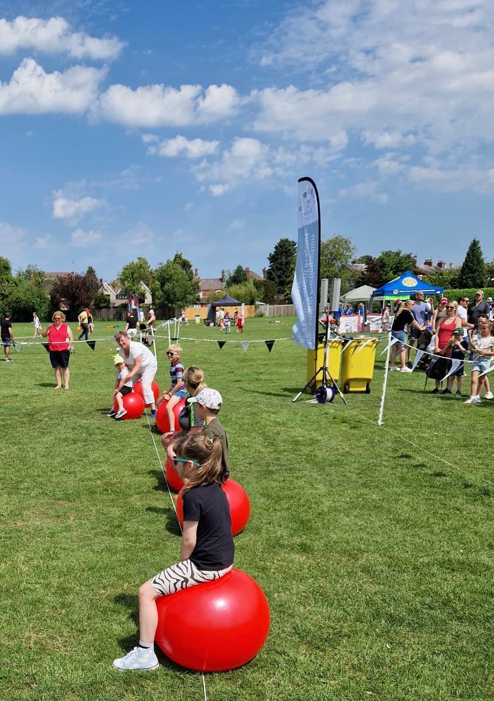 A group of children are sitting on red exercise balls in a field.