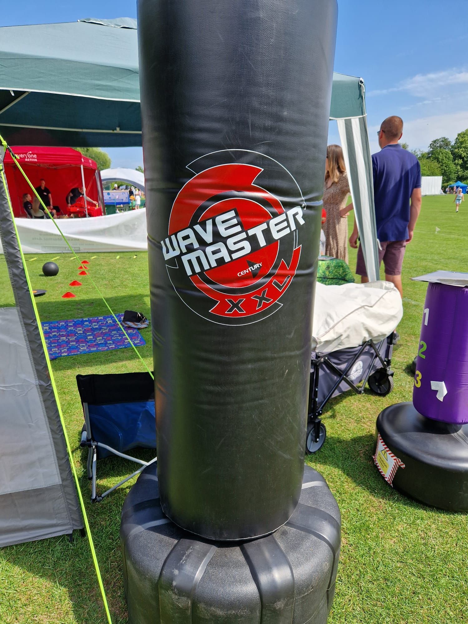 A black boxing bag is sitting on top of a grass covered field.