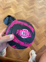 A person is holding a pink and black paceball in their hand.