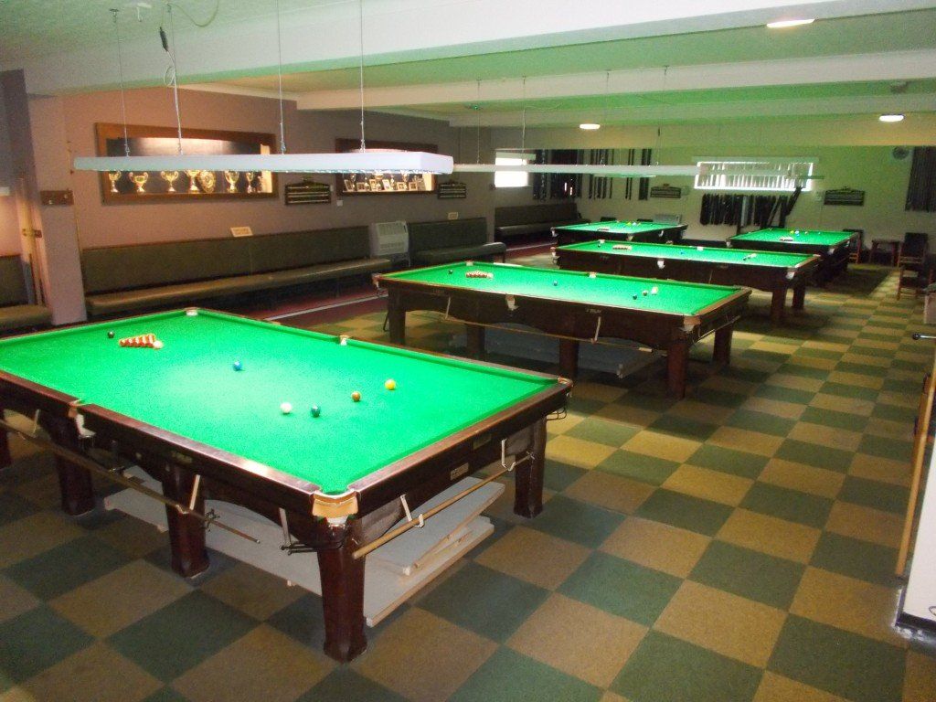 A pool hall with many pool tables and a checkered floor