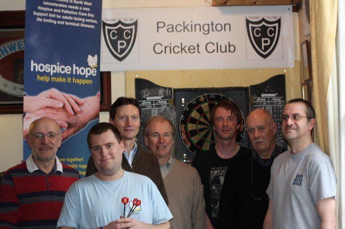 A group of men standing in front of a packington cricket club sign