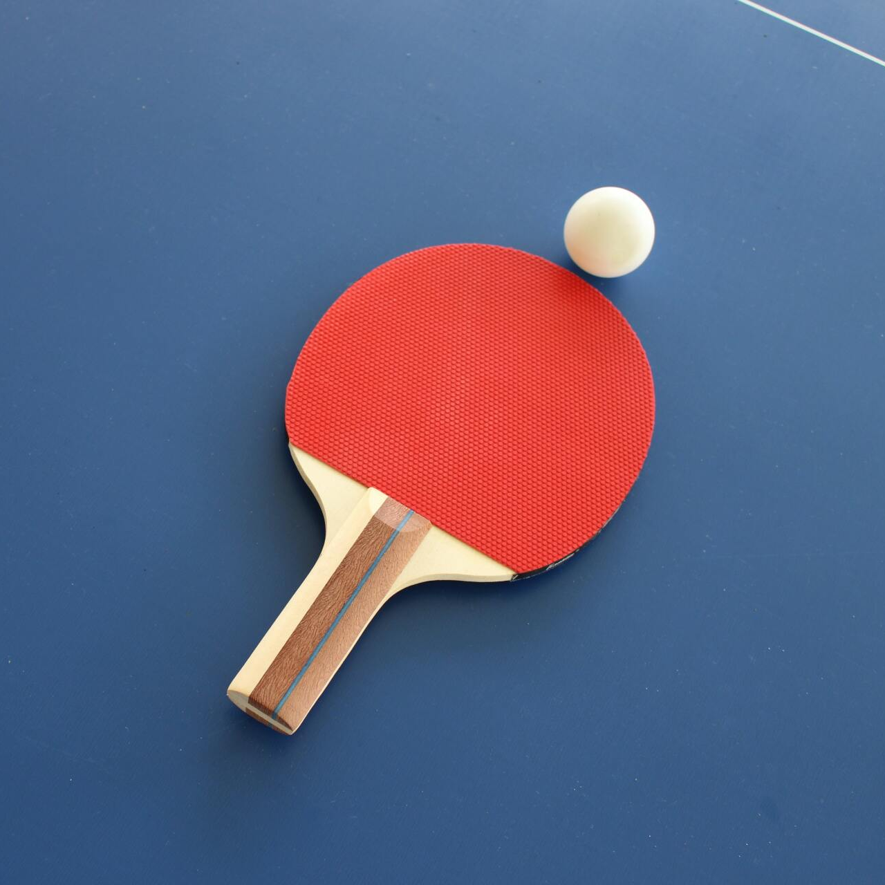 A ping pong paddle and ball on a blue table