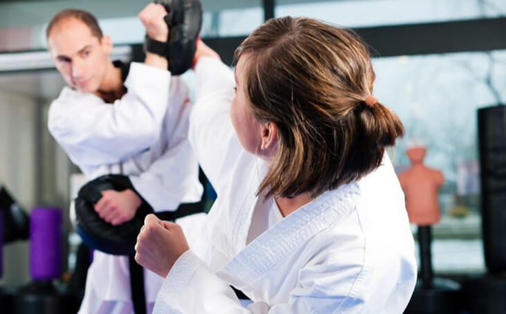 A man and a woman are practicing karate in a gym.
