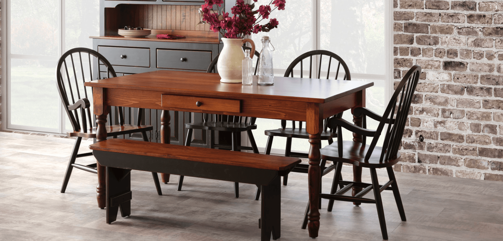 A dining room table and chairs with a bench and a vase of flowers on it.