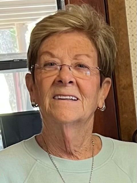 A woman wearing glasses and earrings is smiling for the camera.