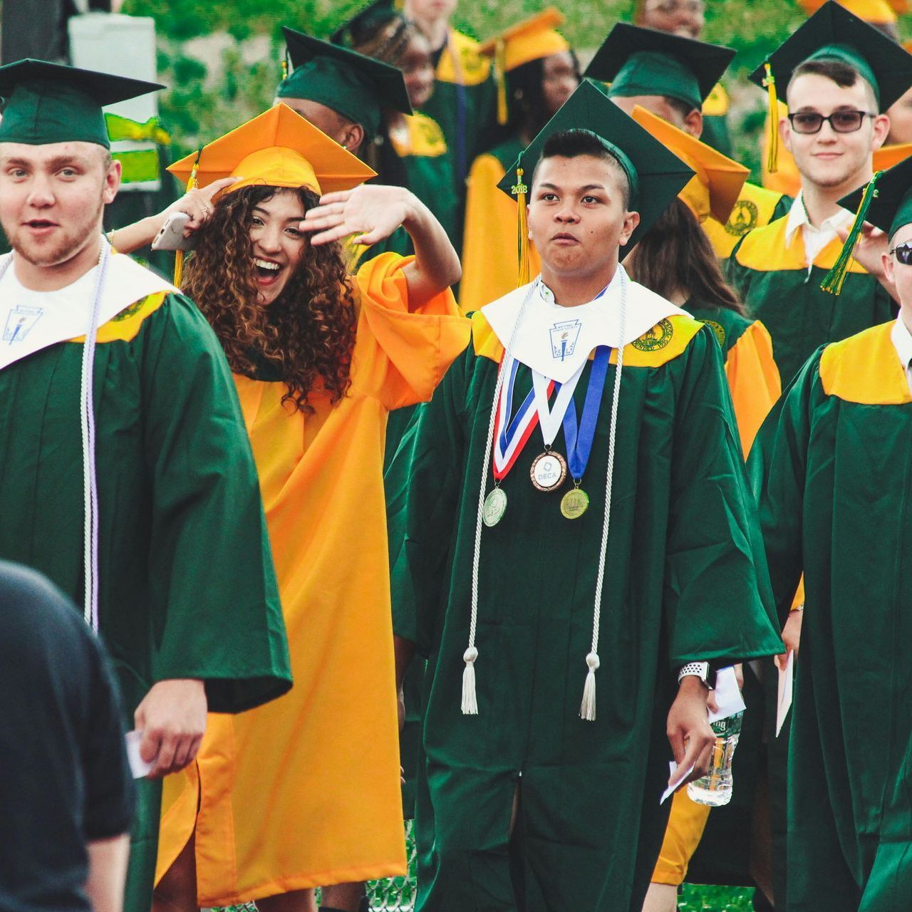 A group of graduates wearing green and yellow gowns