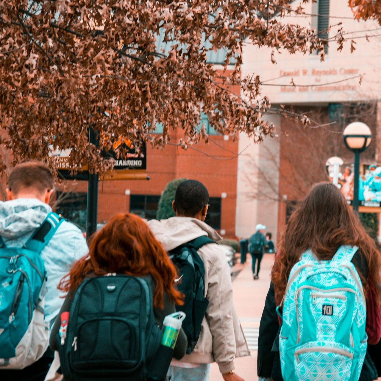 A group of people with backpacks are walking down a sidewalk