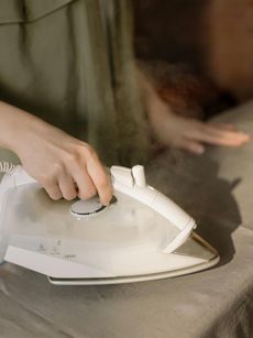 A person is ironing a piece of fabric on a table.