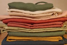 A pile of blankets of different colors are stacked on top of each other.