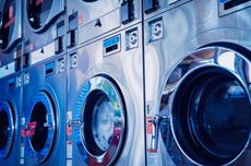 A row of washing machines are lined up in a laundromat.