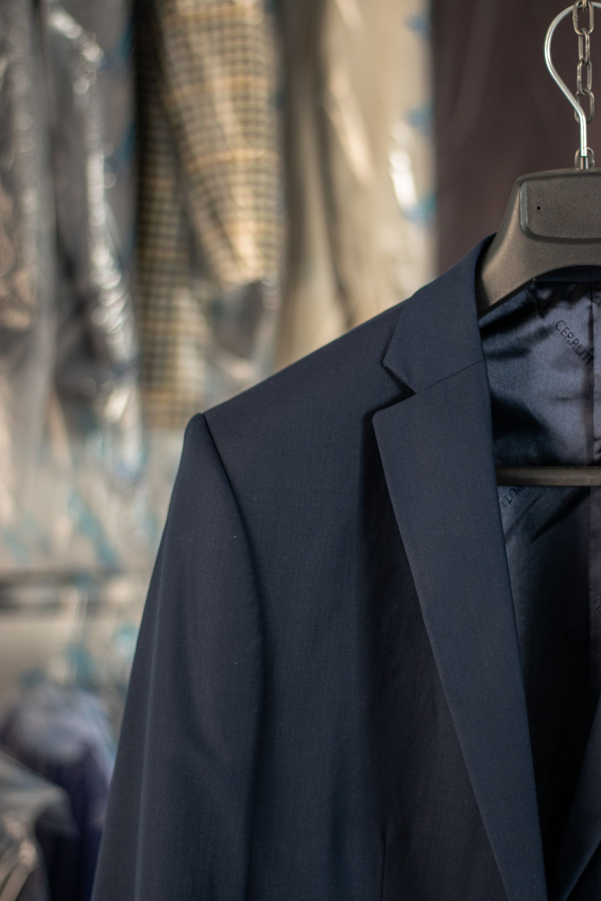 Navy blue suit jacket hanging on a black hanger, dry-cleaned.