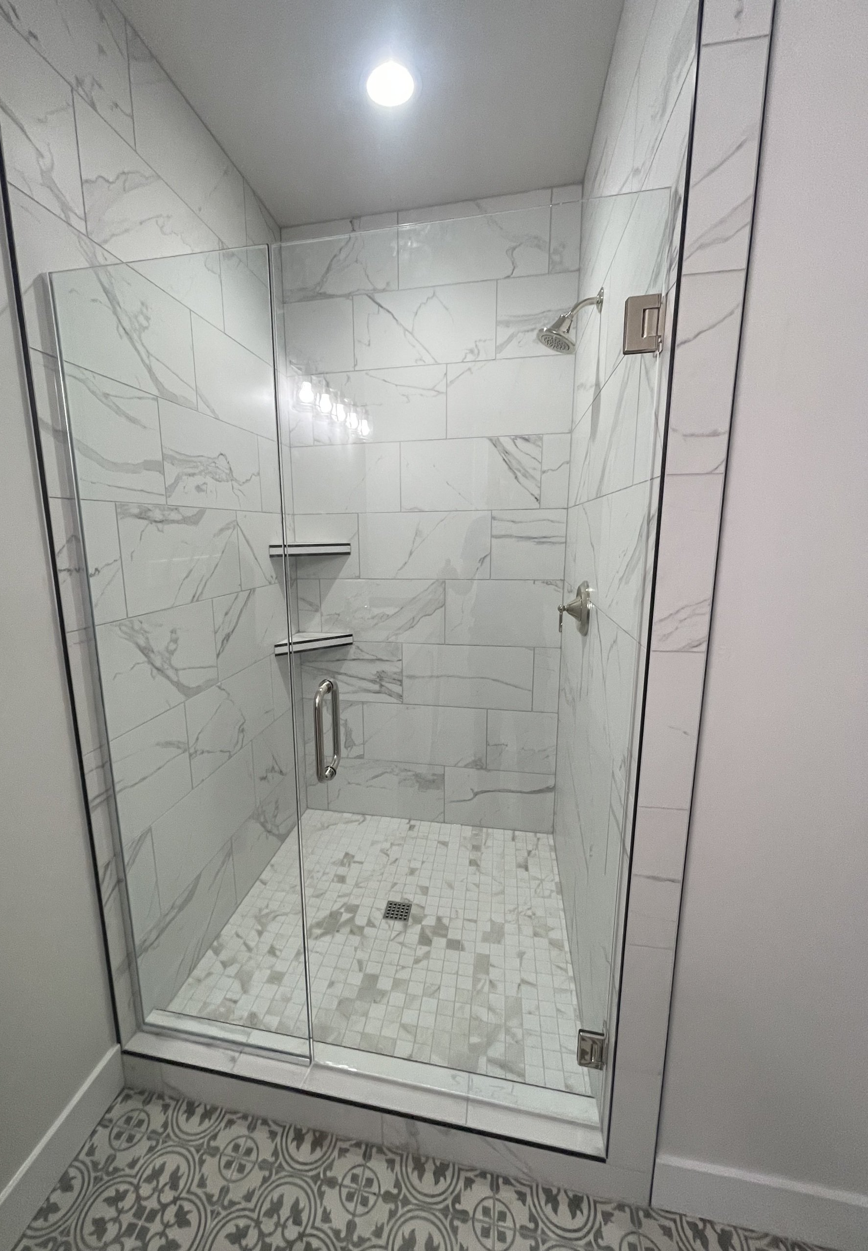 A bathroom with a walk in shower with a glass door.