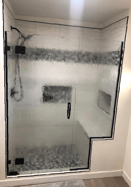 A bathroom with a glass shower door and a bench.